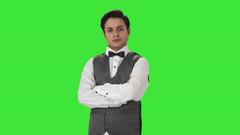 Portrait-of-confident-Indian-waiter-standing-crossed-hands-Green-screen