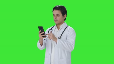 Indischer-Arzt-Scrollt-Durch-Den-Grünen-Bildschirm-Des-Telefons