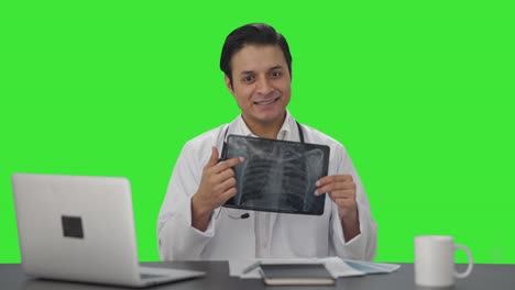 Glücklicher-Indischer-Arzt,-Der-Dem-Grünen-Bildschirm-Der-Kamera-Den-Röntgenbericht-Erklärt