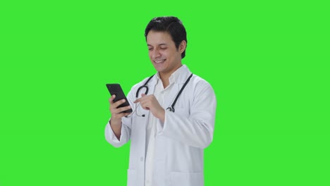 Glücklicher-Indischer-Arzt,-Der-Durch-Den-Grünen-Bildschirm-Des-Telefons-Scrollt