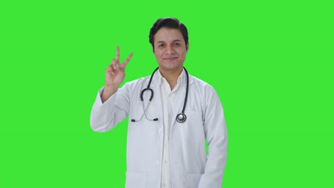 Happy-Indian-doctor-showing-victory-sign-Green-screen