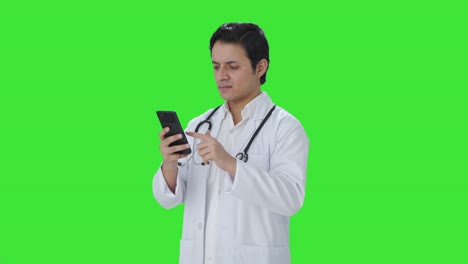 Wütender-Indischer-Arzt-Scrollt-Durch-Den-Grünen-Bildschirm-Des-Telefons