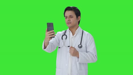 Ernsthafter-Indischer-Arzt,-Der-über-Einen-Videoanruf-Mit-Grünem-Bildschirm-Spricht
