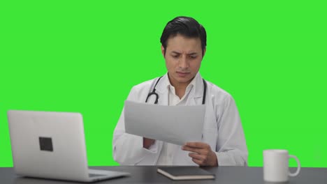 Indischer-Arzt-überprüft-Medizinische-Berichte-Auf-Grünem-Bildschirm