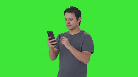 Happy-Indian-man-scrolling-through-phone-Green-screen