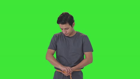 Indian-man-measuring-waist-using-inch-tape-Green-screen