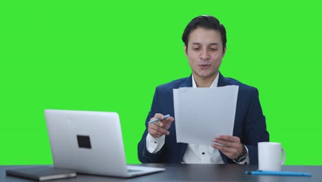 Happy-Indian-manager-reading-and-signing-reports-Green-screen