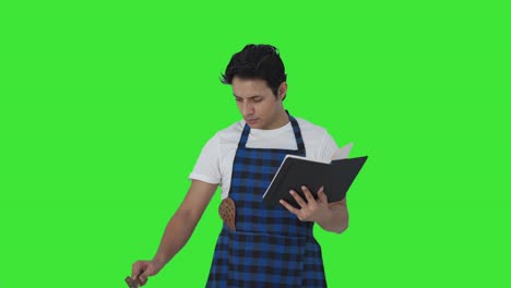 Serious-Indian-cook-making-food-from-recipe-book-Green-screen
