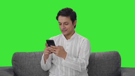 Glücklicher-Indischer-Mann,-Der-Auf-Dem-Grünen-Bildschirm-Des-Telefons-Chattet