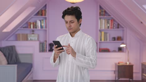 Serious-Indian-man-scrolling-phone