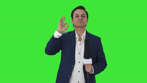 Cheerful-Indian-reporter-showing-okay-sign-Green-screen