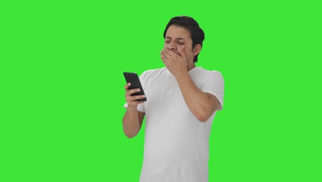 Tired-Indian-man-scrolling-through-phone-Green-screen