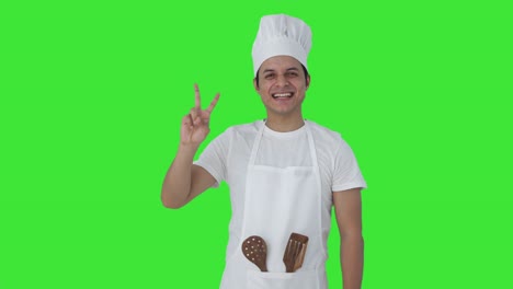Happy-Indian-professional-chef-showing-victory-sign-Green-screen