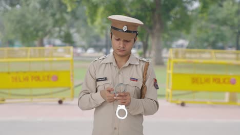 Indischer-Polizist-überprüft-Handschellen