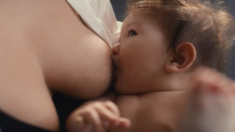 Close-up-of-Asian-baby-breastfed-by-mother-and-playing-with-his-legs