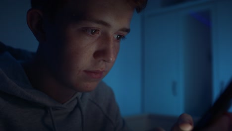 Kaukasischer-Teenager,-Der-Sein-Mobiltelefon-Benutzt,-Während-Er-Nachts-In-Seinem-Zimmer-Sitzt.