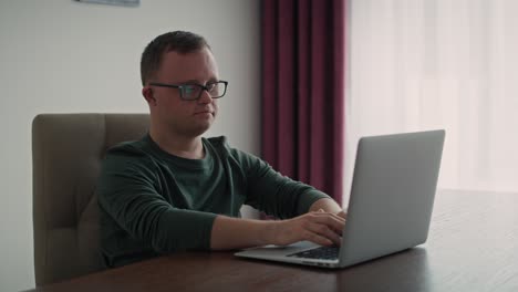 Erwachsener-Kaukasischer-Mann-Mit-Down-Syndrom,-Der-Zu-Hause-Einen-Laptop-Benutzt.