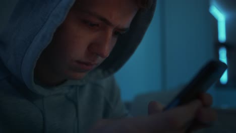 Konzentrieren-Sie-Sich-Auf-Einen-Kaukasischen-Teenager,-Der-Sein-Mobiltelefon-Benutzt,-Während-Er-Nachts-In-Seinem-Zimmer-Sitzt.