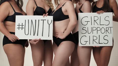 Group-of-unrecognizable-women-wearing-underwear-and-standing-in-the-studio-with-banner.