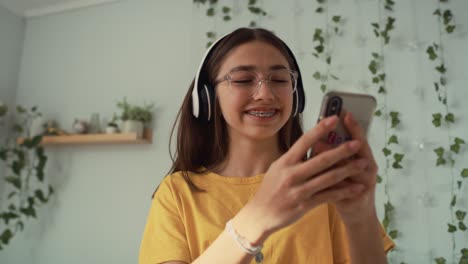 Kaukasisches-Teenager-Mädchen-Tanzt-In-Ihrem-Zimmer-Mit-Kopfhörern-Und-Telefon