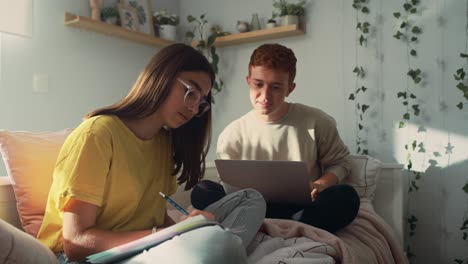 Zwei-Kaukasische-Teenager-Sitzen-Auf-Dem-Bett-Und-Lernen-Gemeinsam-Aus-Büchern-Und-Einem-Laptop.