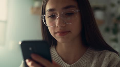 Close-up-of-caucasian-teenage-girl-browsing-phone-in-her-bedroom