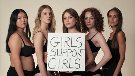 Portrait-of-group-of-women-in-underwear-standing-in-the-studio-and-holding-a-banner