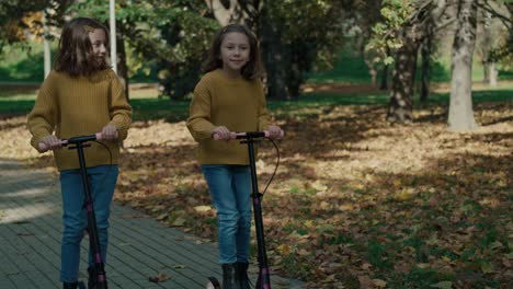 Caucasian-child-siblings-having-fun-in-the-woods-while-driving-a-push-scooter.
