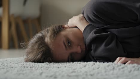 Caucasian-woman-lying-down-at-the-carpet-in-home-with-mental-problem.