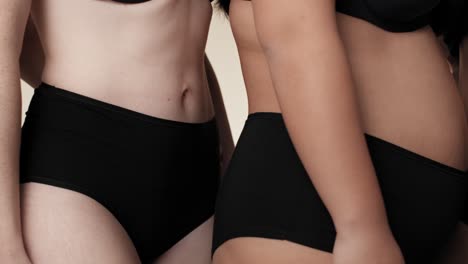 Close-up-of-unrecognizable-women-in-black-underwear-standing-side-by-side