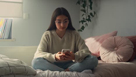 Kaukasisches-Teenager-Mädchen,-Das-Auf-Dem-Bett-In-Ihrem-Schlafzimmer-Sitzt-Und-Telefoniert