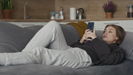 Caucasian-woman-relaxing-on-the-couch-and-using-mobile-phone.