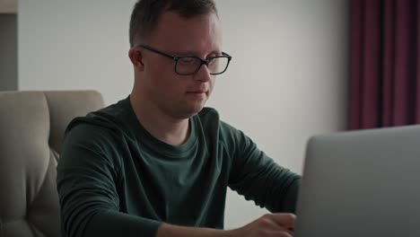 Focus-adult-caucasian-man-with-down-syndrome-using-laptop-at-home.