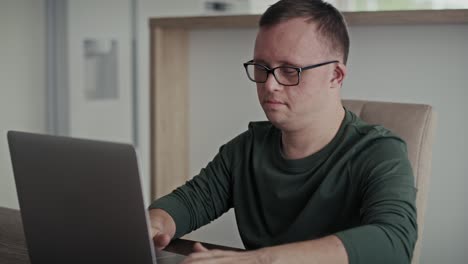 Focus-adult-caucasian-man-with-down-syndrome-typing-on-laptop-at-home.