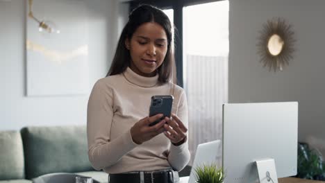 Mixed-race-woman-sitting-on-the-desk-and-browsing-phone