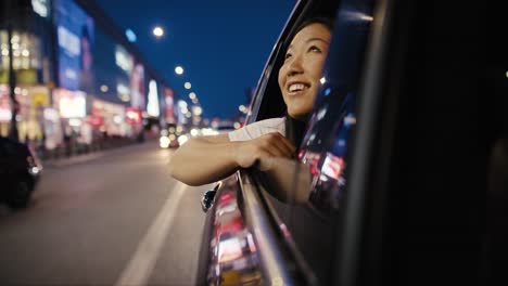 Chinese-woman-riding-in-the-car-at-night-and-admiring-the-city