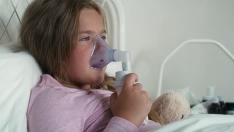 Elementary-age-girl--using-nebulizer-in-bed-at-home