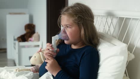 Elementary-age-girl--using-nebulizer-in-bed-at-home.