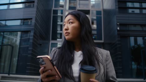 Business-Chinese-woman-standing-on-the-street-in-the-city-and-texting-phone