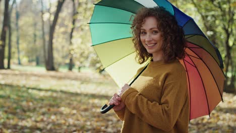 Porträt-Einer-Kaukasischen-Frau-Mit-Buntem-Regenschirm,-Die-Im-Park-Steht.