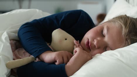 Little-caucasian-girl-sleeping-in-bed-with-teddy-bear.
