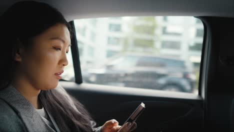 Mujer-China-De-Negocios-Conduciendo-En-Un-Taxi-Y-Haciendo-Una-Llamada-Telefónica