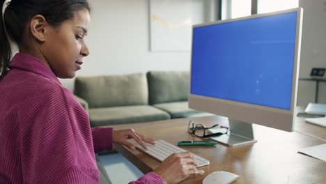 Seitenansicht-Einer-Frau,-Die-Am-Computer-Mit-Blauem-Bildschirm-Arbeitet