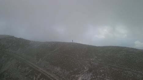 A-man-stands-alone-on-the-ridge-line-of-Lovćen-Mountain-in-Montenegro-as-the-drone-camera-orbits-him