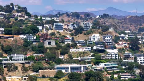 Aerial-view-cutting-across-large-luxury-neighborhood-of-homes-in-Hollywood-hills-daytime-landscape