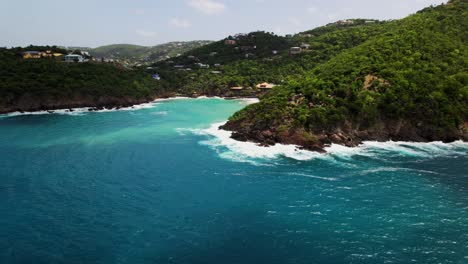 Gorgeous-aerial-view-circling-bluff-water-crashing-on-rocks-homes-in-background-blue-sky-turquoise-water-hills-cliff