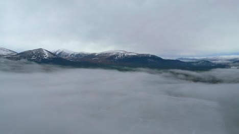 Volando-Sobre-La-Niebla-A-Través-De-Un-Campo-Cubierto-De-Nieve-Hacia-Las-Montañas