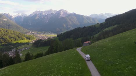 A-camper-van-explores-the-outskirts-of-Toblach,-Italy-in-this-drone-shot