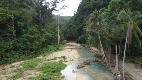 Filipino-women-doing-laundry-and-swimming-in-Creek-blue-water-amid-lush-canyon-jungle-in-Badian,-Cebu