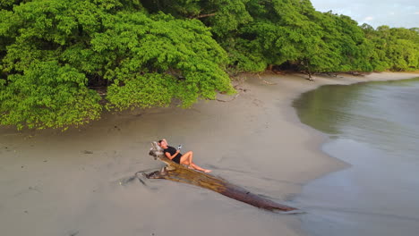 Aerial-view-of-woman-relaxing-on-tranquil-tropical-beach-in-Natural-park,-Manuel-Antonio,-Costa-Rica